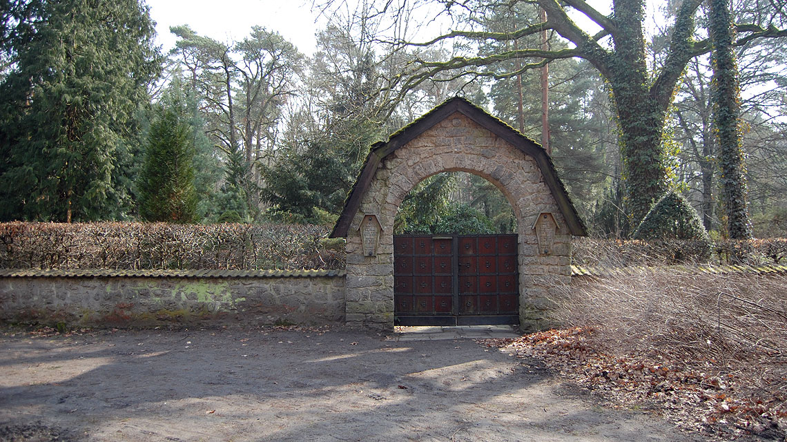 Der Eingang des Friedhofs Grunewald-Forst. Ohne die drei Wegweiser würden Besucher den Ort wohl nicht finden.